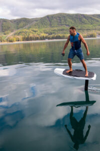 Mann, der ein elektrisches Surfbrett, ein Efoil auf einem See reitet.