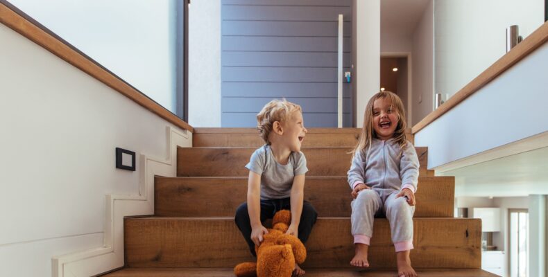 Lachende Kinder auf breiten Holzstufen zeigen, wie wichtig Sicherheit beim Treppen planen sind